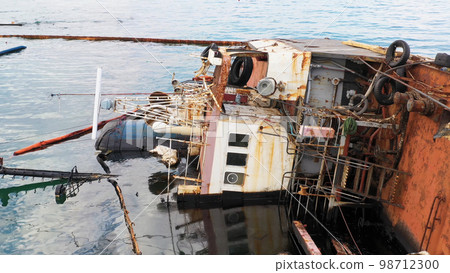 Overturned oil tanker ship in the shallow water. Close up sunken drowned oil tanker after the wreck. Overturned oil tanker ship in the shallow water. Close up sunken drowned oil tanker after the wreck. 98712300