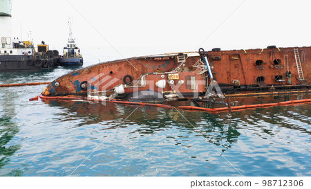 Close up of broken rusty oil tanker ship in the shallow water. Sunken drowned ship after the crash. Close up of broken rusty oil tanker ship in the shallow water. Sunken drowned ship after the crash. 98712306