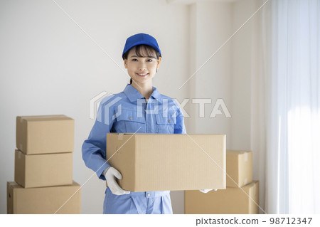 一位身穿工作服的年輕女性拿著一家搬家公司的紙箱圖片 98712347