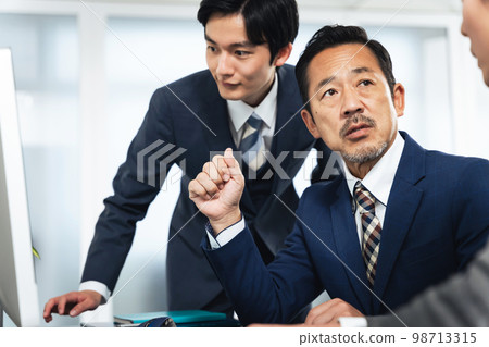 Group of business people having a meeting while looking at the computer screen 98713315
