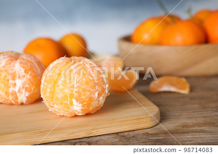 Peeled ripe tangerine on wooden table, closeup. Space for text 98714083