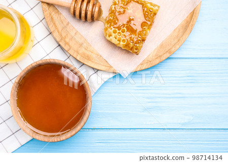 Tasty honey on light blue wooden table, flat lay. Space for text 98714134