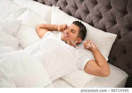 Man awakening on bed at home. Lazy morning Man awakening on bed at home. Lazy morning 98714395
