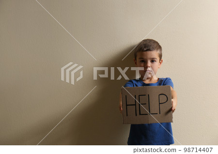 Little boy with sign HELP on yellow background, space for text. Child in danger 98714407