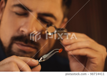 Jeweler working with gemstone on blurred background, closeup 98714411