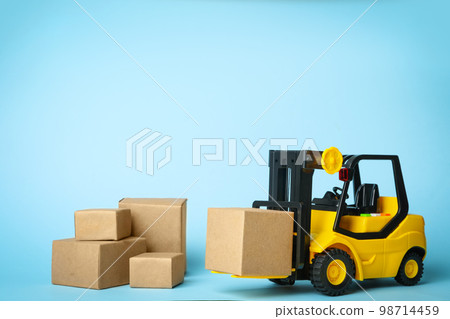 Toy forklift with boxes on blue background. Logistics and wholesale concept 98714459