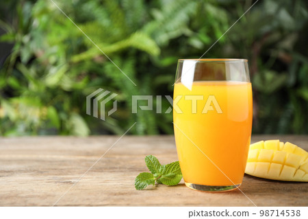 Fresh delicious mango drink on wooden table. Space for text 98714538