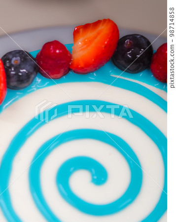 hand pastry chef designer topping a frosted white cake with pastel light blue drip filling bag 98714858