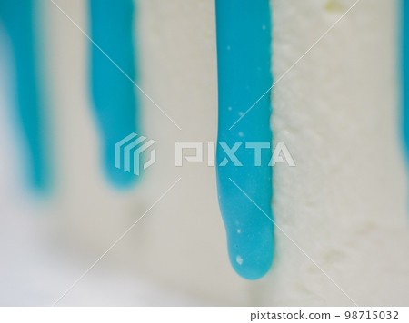 hand pastry chef designer topping a frosted white cake with pastel light blue drip filling bag hand pastry chef designer topping a frosted white cake with pastel light blue drip filling bag 98715032