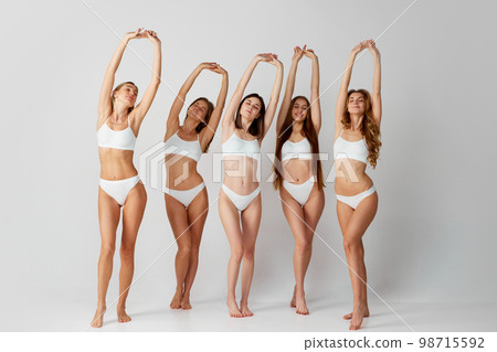Different tone of skin. Group portrait of beautiful pale and tanned women posing in underwear over grey studio background. Concept of natural beauty, body care 98715592