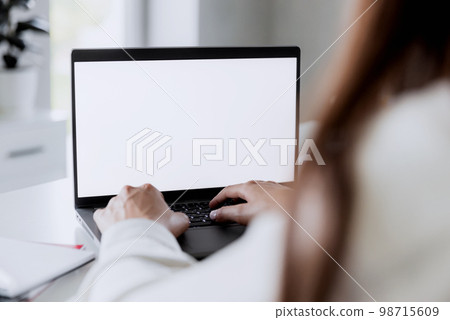 Woman hands typing on the laptop with empty blank white screen mockup. Computer is laying on the white table. Blurred background. Person working from home concept. Copy space area for text Woman hands typing on the laptop with empty blank white screen mockup. Computer is laying on the white table. Blurred background. Person working from home concept. Copy space area for text 98715609