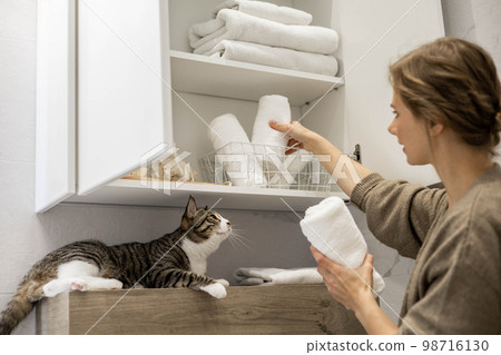 Woman neatly putting or displaying a clean rolled up white towels made from organic cotton. Woman neatly putting or displaying a clean rolled up white towels made from organic cotton. 98716130