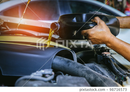 Car mechanic replacing and pouring fresh oil into engine at maintenance repair service station, Car mechanic replacing and pouring fresh oil into engine at maintenance repair service station, 98716573