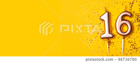 Gold candles in the form of number sixteen on yellow background with confetti. 16 years celebration. Gold candles in the form of number sixteen on yellow background with confetti. 16 years celebration. 98716780