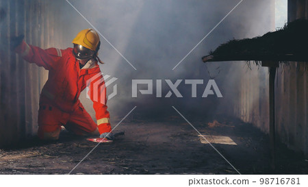Firefighter fighting with fire flame protection property. Fireman wear hard hat, body safe suit uniform for protection from fire operation. Rescue trained in fire fighting extinguisher hazardous fires 98716781