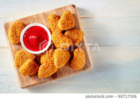 Chicken nuggets with ketchup sauce on a rustic wooden table, shot from above 98717306