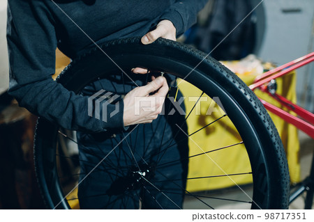 Mechanic repairman assembling wheel nipple rim custom bicycle in workshop 98717351