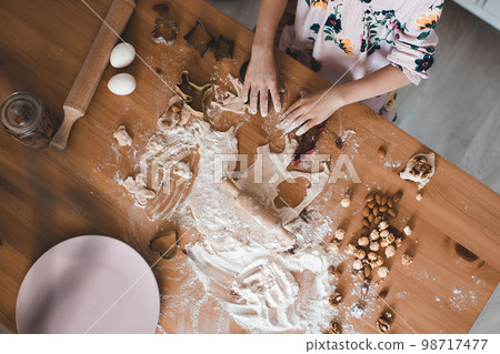 Girl making cookies with raw dough on wooden table closeup. Top view. 98717477