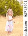 Little baby girl 2-3 year old walking in meadow. Nature. Looking at camera. Childhood. 98718001
