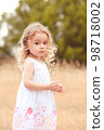 Cute little girl walking in meadow outdoor 98718002