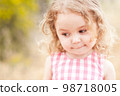 Close up portrait of cute baby girl 2-3 year old posing outdoors. Cute child. Looking away. Childhood. 98718005