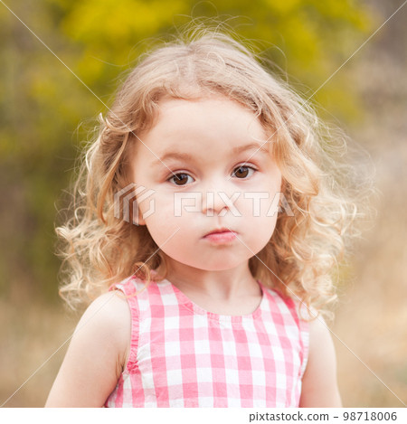 Baby girl 2-3 year old looking at camera over nature background outdoors. Childhood. Baby girl 2-3 year old looking at camera over nature background outdoors. Childhood. 98718006