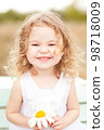 Baby girl 2-3 year old playing the ape outdoors. Looking at camera. Childhood. 98718009