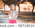 Smiling baby girl 4-5 year old posing outdoors over nature background. Looking at camera. Childhood. 98718010