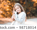 Pretty child girl 5-6 year old holding cute toy rabbit outdoors. Looking at camera. Childhood. 98718014
