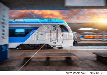 Blue high speed train in motion on the railway station at sunset Blue high speed train in motion on the railway station at sunset 98718175
