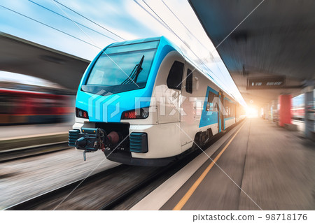 Blue high speed train in motion on the railway station at sunset Blue high speed train in motion on the railway station at sunset 98718176