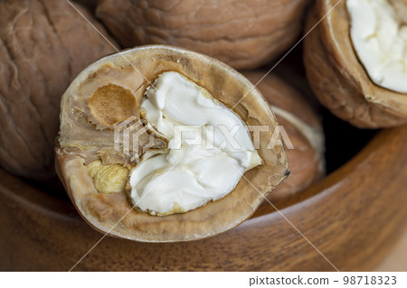 Open and broken walnut shells lying on the table Open and broken walnut shells lying on the table 98718323