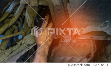 Technician change car oil filter under car. Technician change car oil filter under car. 98718591
