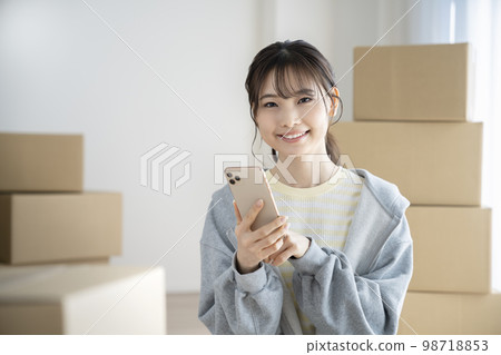 一位微笑的年輕女子拿著智能手機看著相機 移動圖像 一位微笑的年輕女子拿著智能手機看著相機 移動圖像 98718853