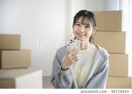 A smiling young woman holding a smartphone and looking at the camera Moving image A smiling young woman holding a smartphone and looking at the camera Moving image 98718854