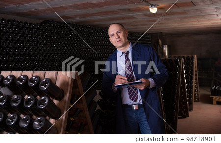 Winemaker with clipboard in winery vault Winemaker with clipboard in winery vault 98718901