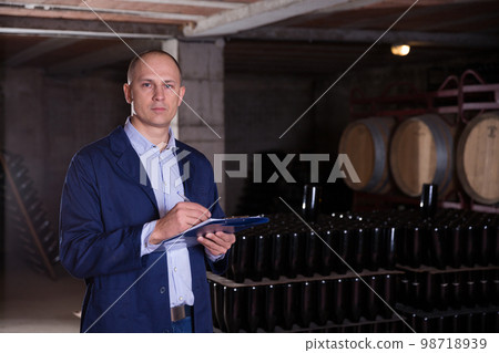 Wine producer with clipboard in wine cellar 98718939