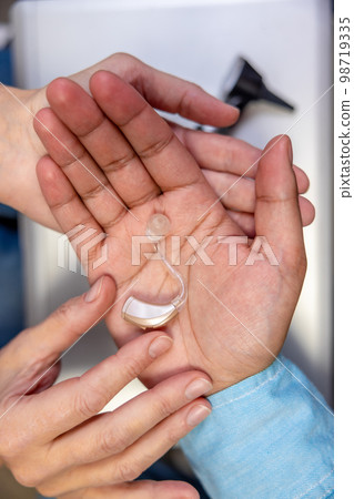 Close up of a hearing aid on males hand 98719335