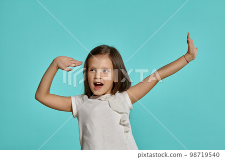 Close-up studio shot of beautiful brunette little girl posing against a blue background. Close-up studio shot of beautiful brunette little girl posing against a blue background. 98719540