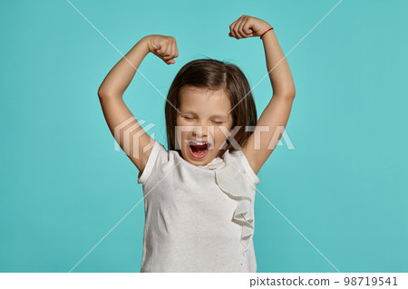 Close-up studio shot of beautiful brunette little girl posing against a blue background. 98719541