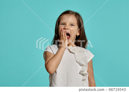 Close-up studio shot of beautiful brunette little girl posing against a blue background. 98719543