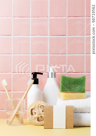 Natural soap and cosmetics bottles, cotton towels, eco friendly body care on table inside a bathroom wall tiles ceramic background Natural soap and cosmetics bottles, cotton towels, eco friendly body care on table inside a bathroom wall tiles ceramic background 98719562