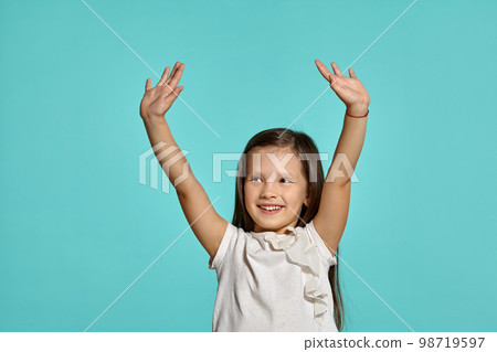 Close-up studio shot of beautiful brunette little girl posing against a blue background. Close-up studio shot of beautiful brunette little girl posing against a blue background. 98719597