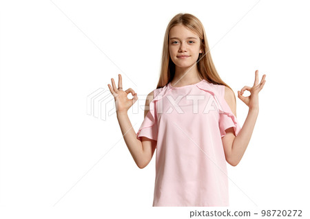 Studio portrait of a beautiful girl blonde teenager in a pink t-shirt posing isolated on white background. 98720272
