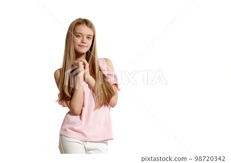 Studio portrait of a beautiful girl blonde teenager in a pink t-shirt posing isolated on white background. 98720342