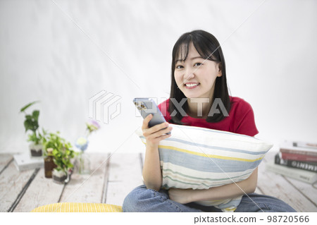 Young woman looking at her smartphone in the living room Young woman looking at her smartphone in the living room 98720566