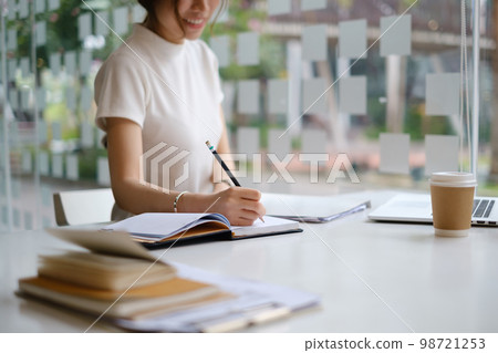 Young female college taking notes and using highlighter. Focused student in online class room. Authentic Education concept. 98721253