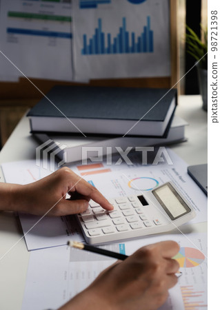A business woman accountant or banker does an audit and calculates expenses for a financial report balance sheet statement using a calculator. The principle of saving and investing. A business woman accountant or banker does an audit and calculates expenses for a financial report balance sheet statement using a calculator. The principle of saving and investing. 98721398