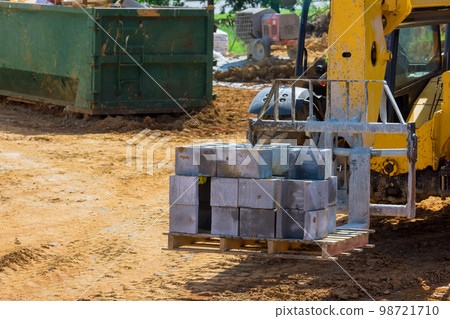 Boom forklift moving cement blocks to place of installation of wall of house Boom forklift moving cement blocks to place of installation of wall of house 98721710