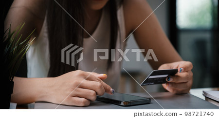 Woman enjoy with online shopping application and looking at credit card for fill number to payment. Woman enjoy with online shopping application and looking at credit card for fill number to payment. 98721740